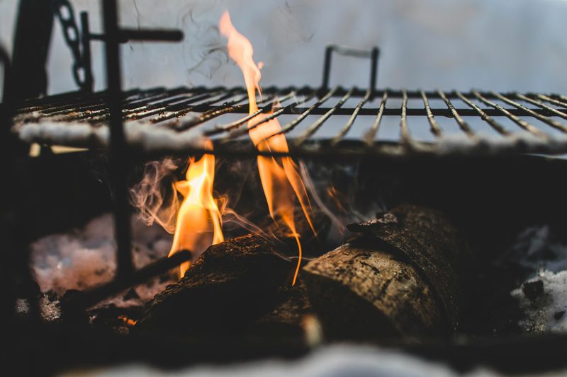 A fire pit with a grill plate over burning logs