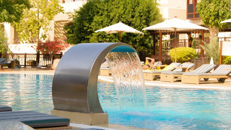 A stainless steel water blade feature beside a pool