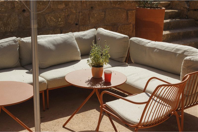 A cream and terracotta outdoor sofa set against a stone wall