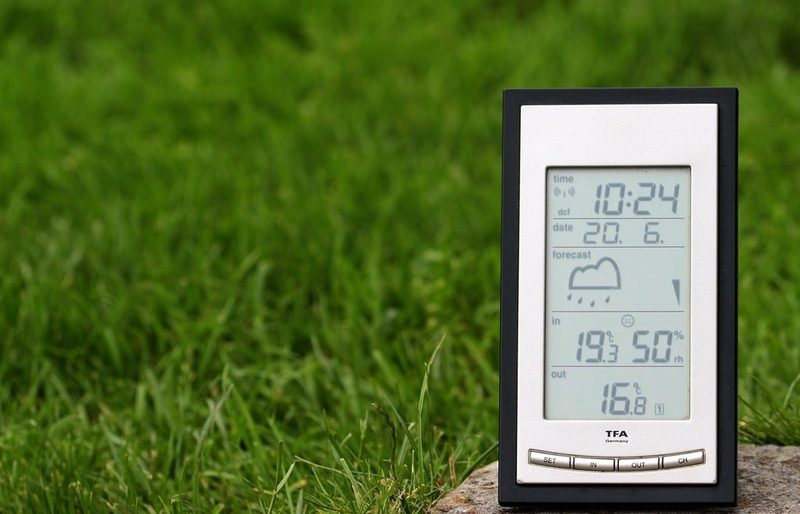 A digital weather station display standing on a lawn