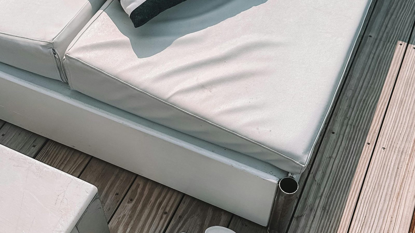 A sun lounger on a timber deck beside greenery