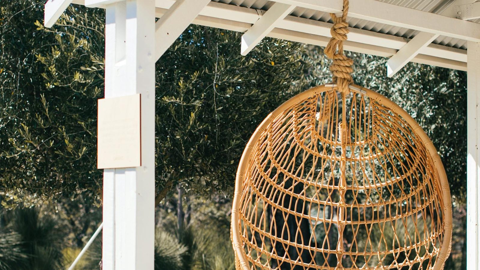 A hanging egg chair in a garden pavilion