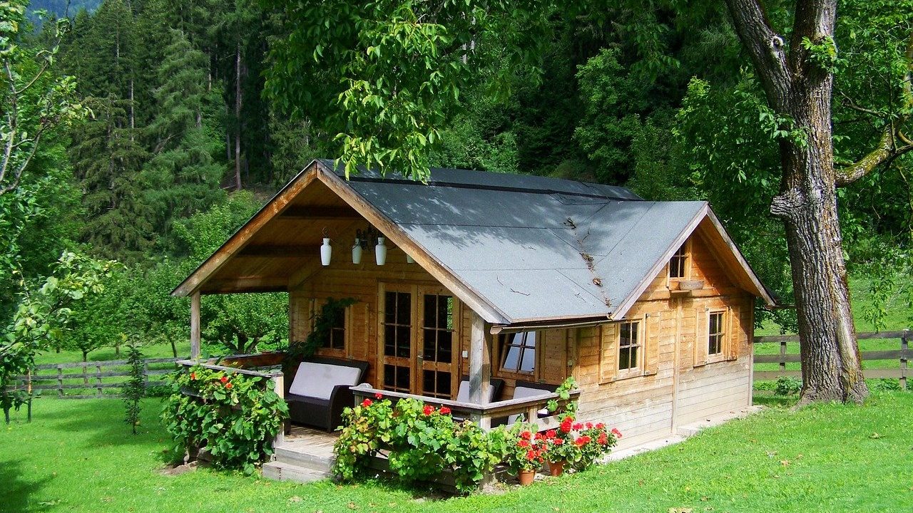 A timber garden cabin on a lawn surrounded by trees